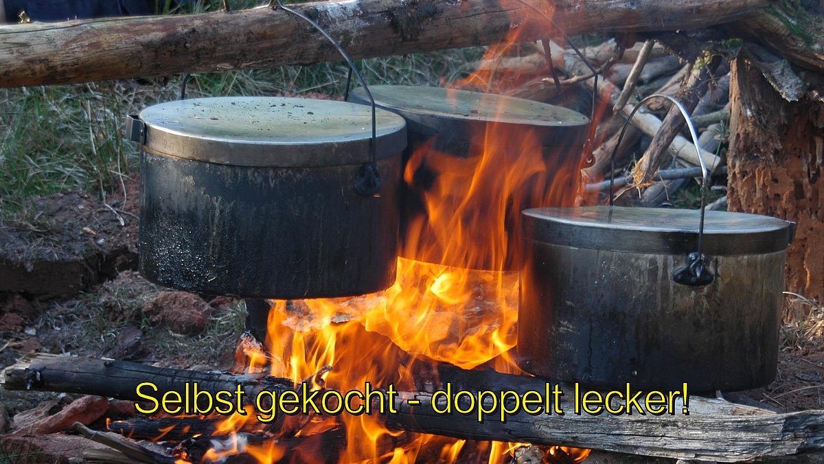 Pfadfinderkochtöpfe über einem lodernden Feuer.